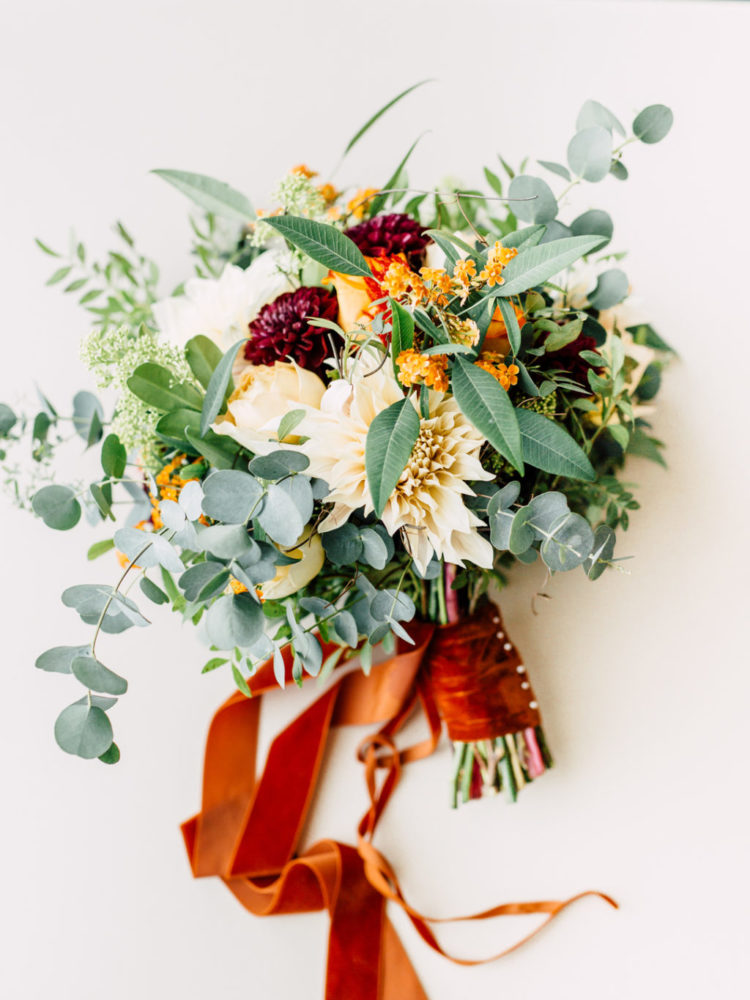 This lovely wedding bouquet was done with burgundy, orange and creamy blooms and a bright orange ribbon