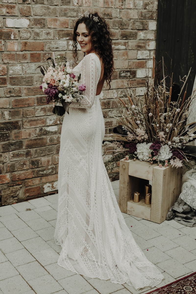 The bride was wearing a boho lace sheath wedding dress with long sleeves and a cutout back plus gorgeous headpieces