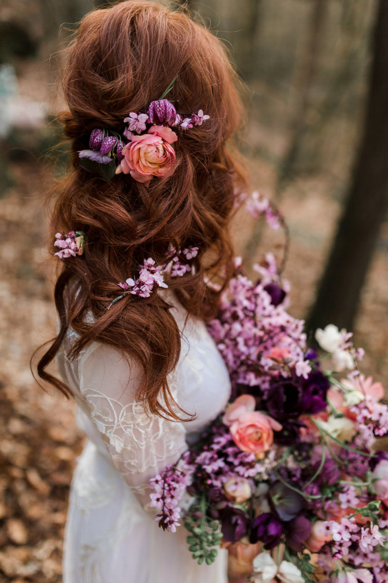 The wavy and relaxed wedding hairstyle was spruced up with purple and orange blooms
