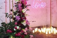 06 a beautiful wedding ceremony space with candles, an arch, lush florals in red, burgundy and pink and a pink neon sign
