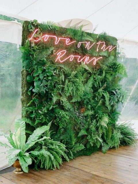 a lush greenery wall with a red neon sign is a very fresh and cool wedding decor idea