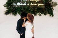 10 a modern boho wedding backdrop with tropical leaves and a neon sign is a fun idea