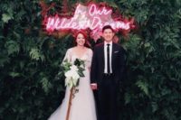 11 a modern wedding backdrop of lush greenery and a red neon sign is a statement idea