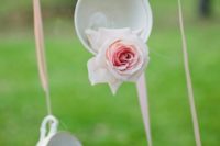 13 suspended vintage teacups with pink roses on ribbons is a beautiful decor idea for a dessert wedding