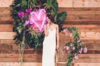 17 a lovely wedding decoration with a round tropical greenery wreath and a pink neon heart in the center