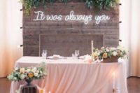 18 a rustic wooden wall with greenery decor and a neon sign for the reception or sweetheart table backdrop
