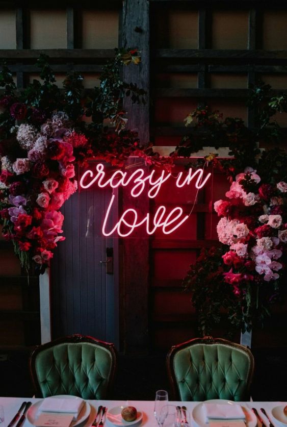 a wedding arch moved to the reception to spruce it up with its bold florals and a bold neon sign