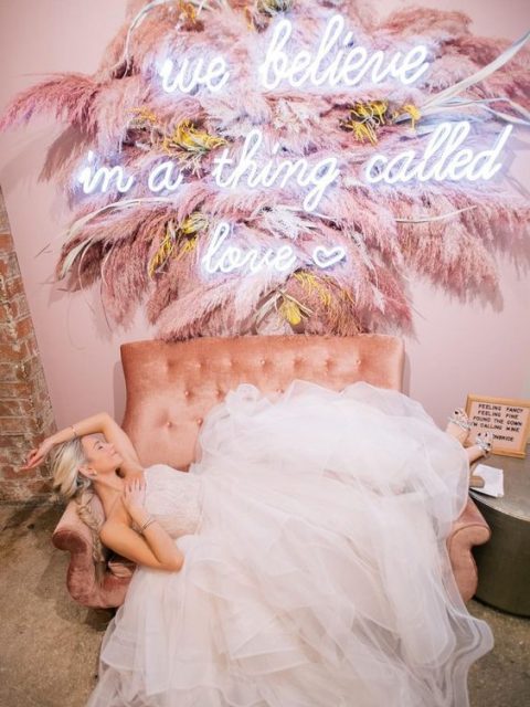 a wedding lounge with a pink sofa and a gorgeous decoration with pink pampas grass and a neon sign