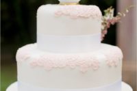 24 a vintage-inspired wedding cake with pink sugar lace, ribbons and a teacup with blooms on top