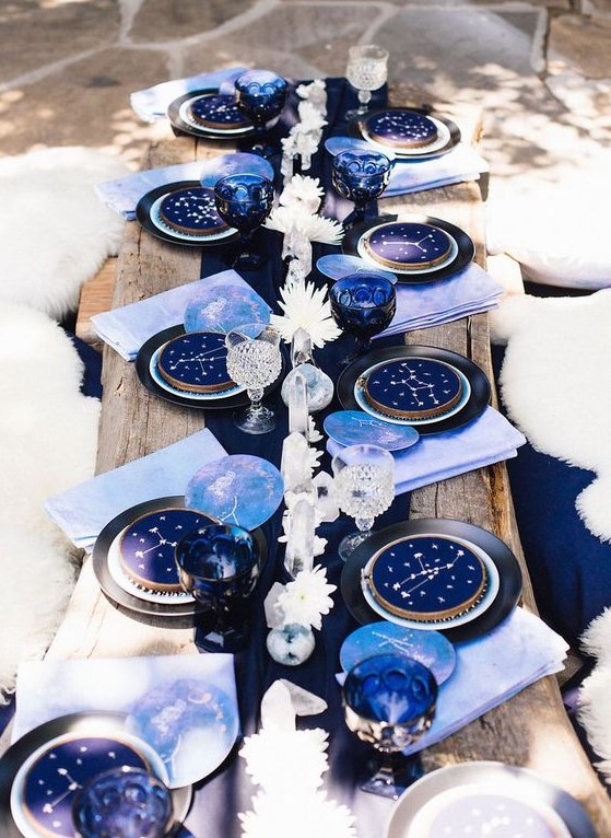 a bold puple and navy wedding tablescape with white blooms, constellation plates, lilac napkins and a navy runner
