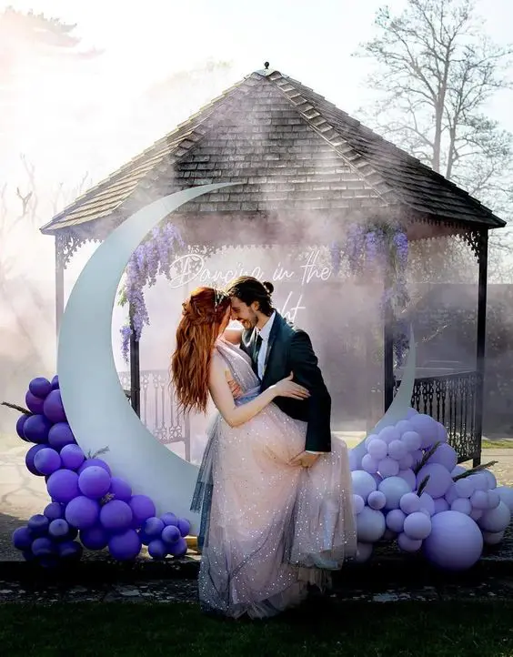 a bold wedding altar of a half moon and purple and lilac balloons around plus a neon sign in the backdrop for a celestial wedding
