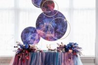 a bright wedding tablescape with a pink, teal and blue tulle tablecloth, celestial spheres and bold blooms on the table