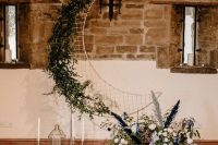 a celestial wedding backdrop of a half moon, neutral blooms and greenery, pampas grass, candles and candle lanterns
