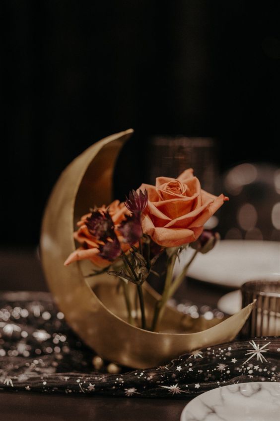 a celestial wedding centerpiece of a gold half moon and some roses is a catchy and cool idea for a celestial wedding
