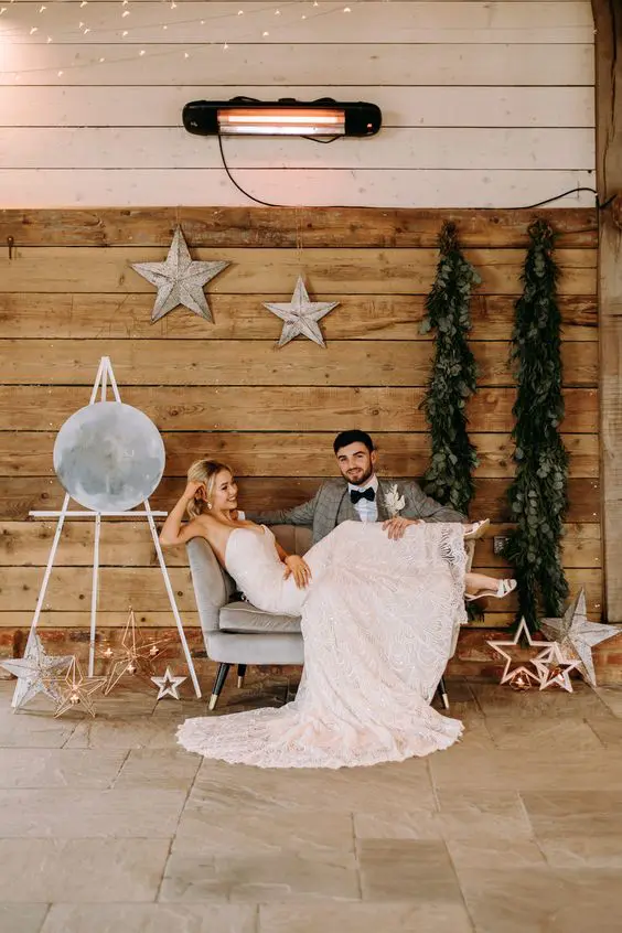 a celestial wedding lounge with a love seat, stars and star candle lanterns, a moon sign and greenery