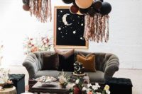 a celestial wedding lounger with a grey sofa, side tables and a black pouf, balloons, an artwork and some blooms