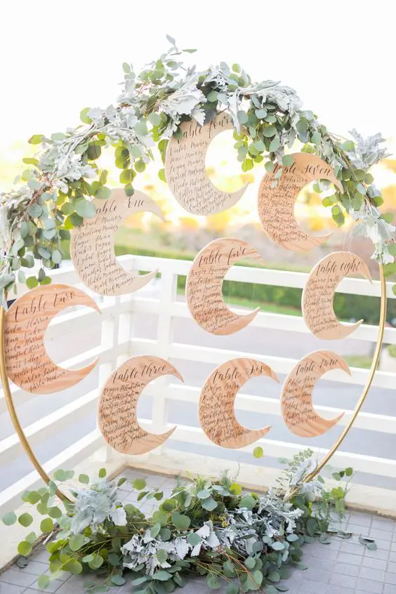 a celestial wedding seating chart with greenery and half moons is a lovely solution for a celestial wedding