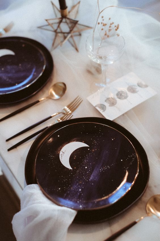 a celestial wedding tablescape with purple and gold porcelain, moons, stars and black and gold cutlery