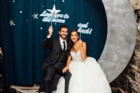 a cute photo booth setting with a crescent moon and stars and matching props for a wedding
