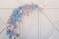 a pastel half moon wedding altar with white, blue and blush flowers and pampas grass is a cool spring wedding decor idea