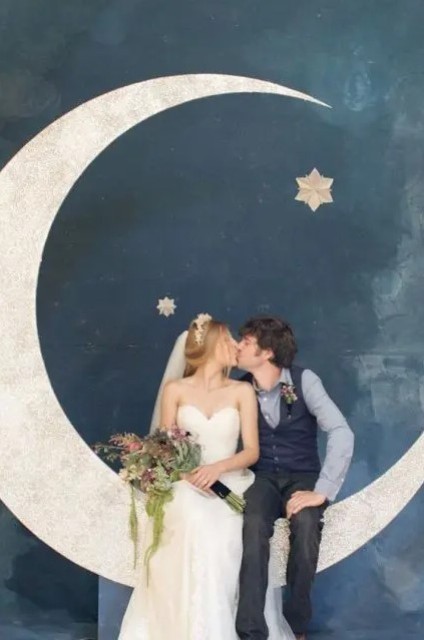 a photo booth with a large half moon and stars, metallic ones to stand out in a dark backdrop
