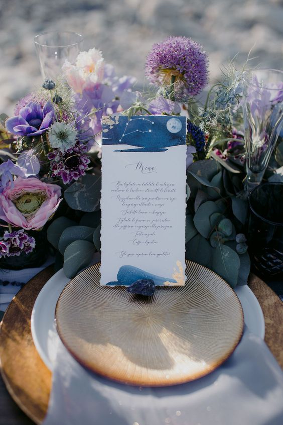 a purple celestial wedding table setting with porcelain, purple and pink blooms, greenery and a constellation card