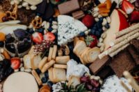 an epic grazing table with cheese, fruits, berries, bread, crackers and nuts and chocolate