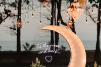 celestial wedding decor with a half moon marquee, bulbs and star-shaped lights plus white floral arrangements