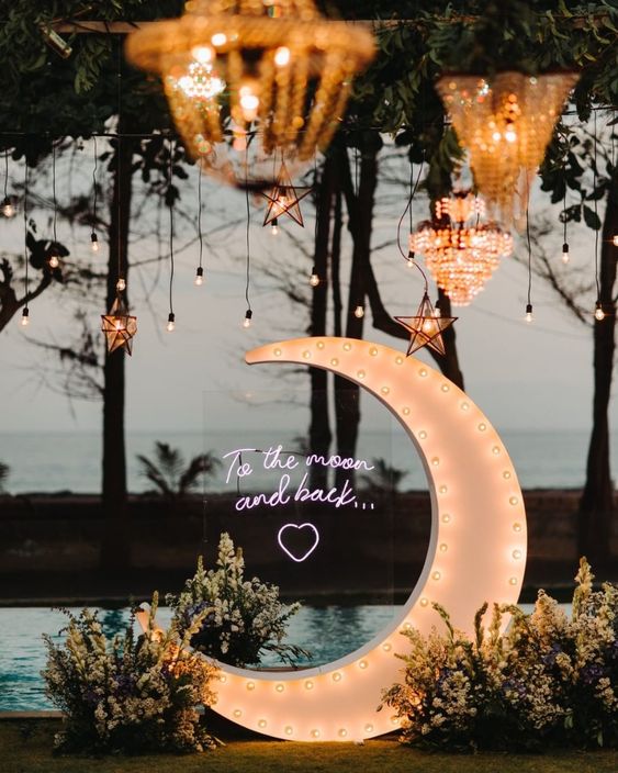 celestial wedding decor with a half moon marquee, bulbs and star-shaped lights plus white floral arrangements