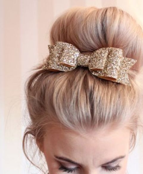 a large top knot highlighted with a gold glitter ribbon and a bow on top looks timeless and very chic