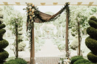 04 The wedding arch was decorated with burlap, blooms, greenery and with candles on the ground