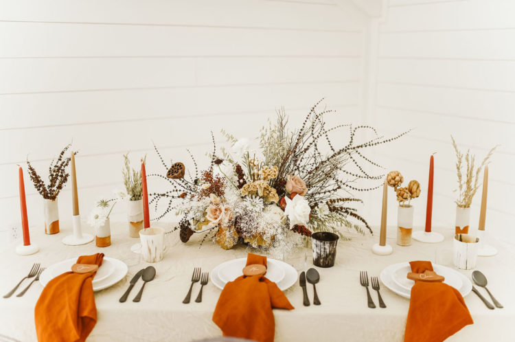 The wedding tablescape was done with color block details, muted candles, dried and fresh florals and terra cotta napkins