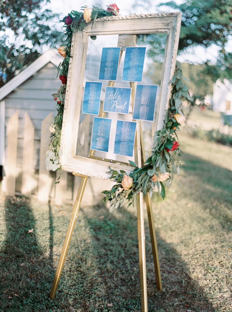 The wedding seating chart was done in navy and copper and decorated with greenery and bright blooms