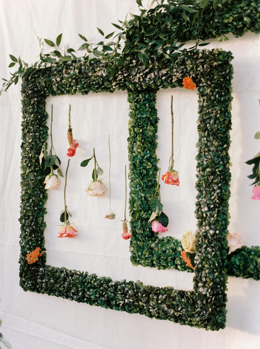 What a pretty wedding decoration of greenery frames with flowers hanging down