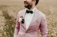 10 tan pants, a pink blazer, a polka dot black bow tie and a floral boutonniere for a chic summer groom’s outfit