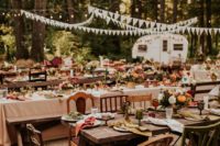 11 a 70s inspired lodge wedding reception with banners, lights, mismatching chairs, colorful glasses and blooms and muted color napkins