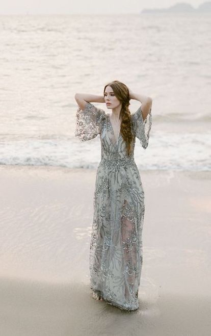 a grey embellished wedding dress with a deep neckline, bell sleeves and an illusion skirt for a coastal bride