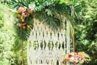 13 a bold 70s tropical wedding backdrop with torpical leaves, blooms, a macrame backdrop and lush florals
