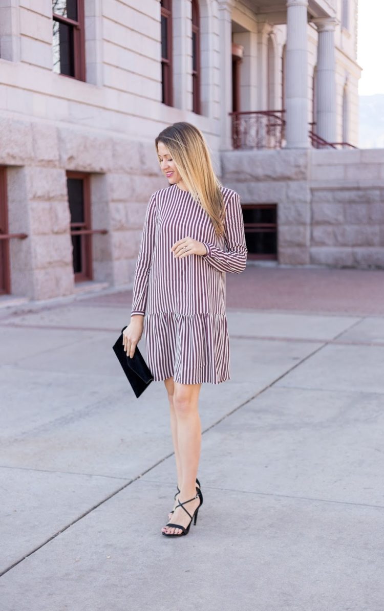 a striped burgundy and white drop waist over th eknee dress, black strappy shoes and a black velvet clutch for a fall wedding