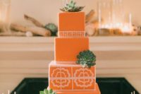20 a coral wedding cake with floral and geometric patterns and succulents on a white stand for a 70s wedding