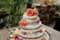 22 a naked wedding cake decorated with muted colored blooms, greenery and lots of petals