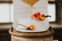 24 a white wedding cake accented with bold blooms and yellow knit hearts as toppers that brign that 70s feel to the wedding