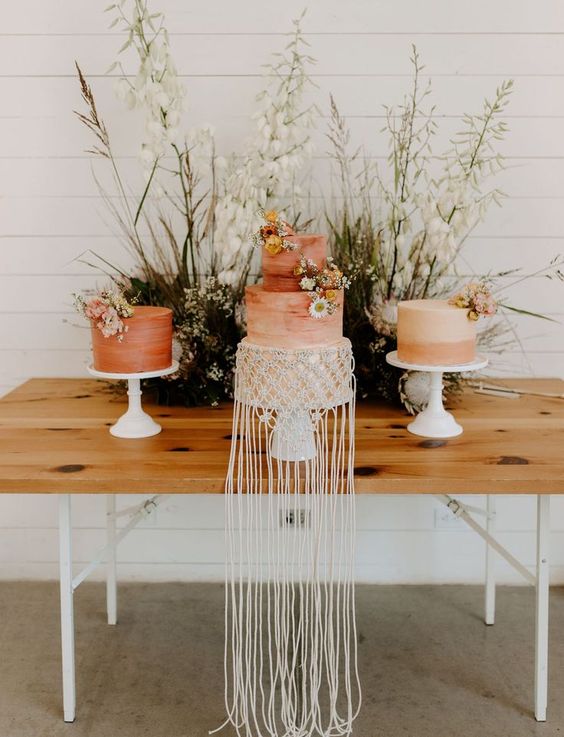 Coral brushstroke and ombre wedding cakes decorated with dried blooms and macrame with long fringe