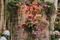 The wedding backdrop was done with colorful yarn and blooms, with a neon sign and greenery on top