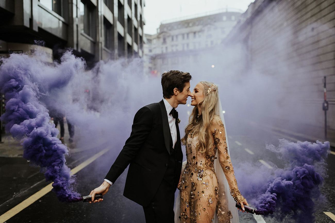 a beautiful wedding portrait with purple smoke bombs create an impression that there's nobody else here