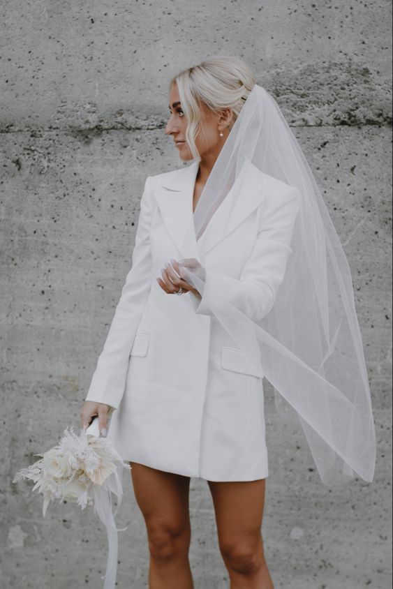 a blazer mini wedding dress paired up with a veil are a cool wedding ensemble for a casual wedding