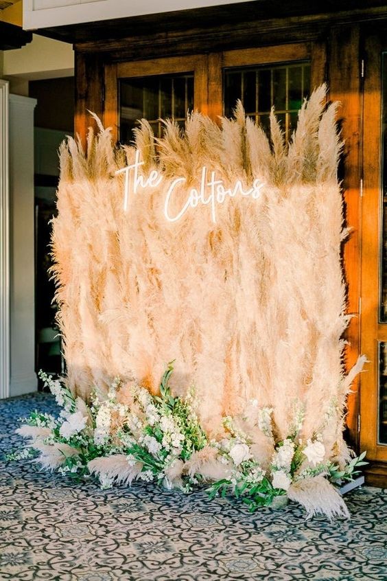 a boho wedding backdrop of pampas grass, white blooms and grasses, a neon sign is amazing for a wedding