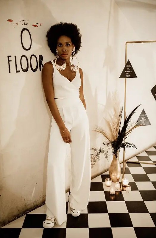 a bold and catchy bridal look with high waisted wideleg pants, a crop top with thick straps and a deep neckline, sneakers and oversized earrings