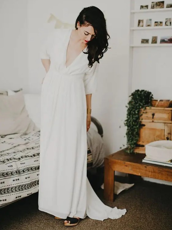 a casual A-line wedding dress with a depe neckline, short sleeves and a draped bodice and skirt is a lovely idea for a modern bride