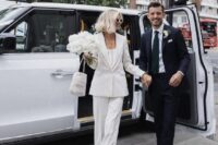 a casual bridal look with a white pantsuit, a top and heels plus a small beaded bag and a white peony wedding bouquet